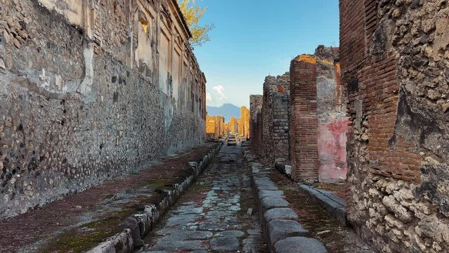 Dolly forward shot between old rustic street walls in Pompeii and Mount Vesuvius VOlcano in background