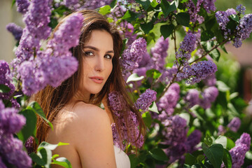 Outdoor fashion photo of beautiful young woman surrounded by flowers. Spring blossom