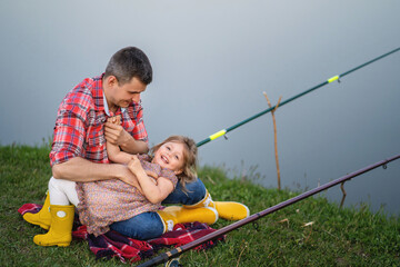 Family portrait. Father with daughter fishing on the lake