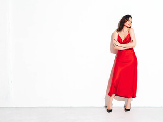 High fashion portrait of young beautiful brunette woman wearing nice trendy red evening dress. Sexy fashion model posing in studio. Fashionable female isolated on white