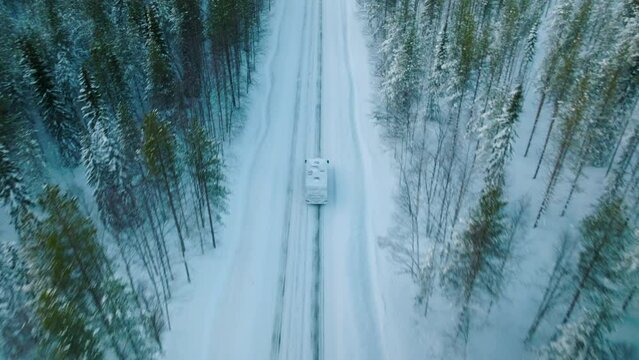 White Camper Driving On Snowy Road In Lapland Finland - aerial shot