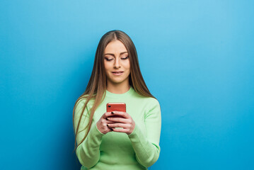 Woman using her mobile phone while standing over an isolated background. Technology concept.