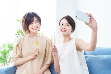 Two women taking a picture with a champagne glass in their hands