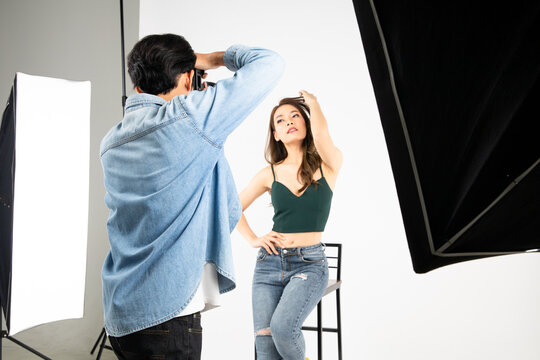 Model young woman posing for photo taken with professional photographer in studio.