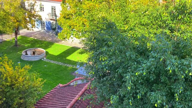 Beautiful little garden square with a water fountain, trees and traditional typical portuguese houses with orange roofs in the city center of Lisbon, 4K tilting up