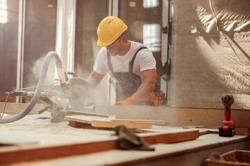 Male worker using wood cutting circular saw machine in workshop