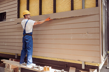 Handsome man builder building cabin at construction site