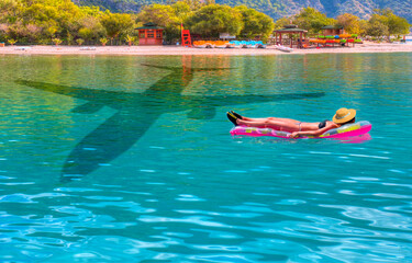 Beautiful girl sunbathing on the bach - Airplane travel to exotic destination with shadow of passenger airplane flying above beautiful tropical beach 
