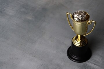 Brain inside gold cup trophy with copy space. Winning mentality and mindset concept.