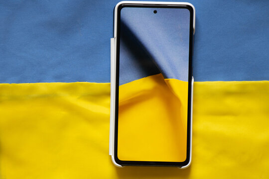 The national flag of Ukraine is yellow-blue on the screen of a smartphone on the background of the flag of Starna, peace and stop war, patriotism