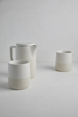 Big set of empty white ceramic plates and other tableware different size and shapes over white linen tablecloth. Flat lay