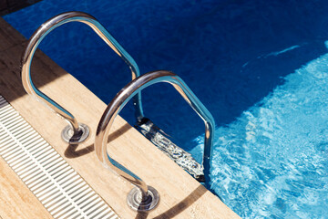 Grab bars ladder in the swimming pool on a sunny day
