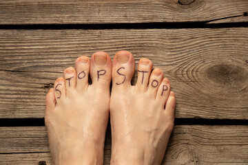 Women's feet are bare on the floor at home with the text stop, stop