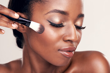 Brush on more of your beauty. Studio shot of a beautiful young woman applying blush with a makeup brush.