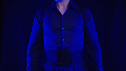 Headless person in blue shirt wearing posture belt on black background