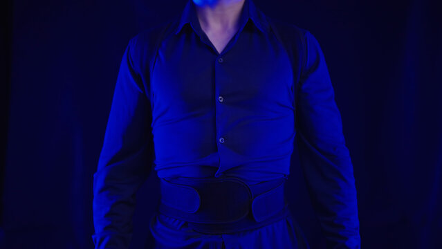 Headless person in blue shirt wearing posture belt on black background