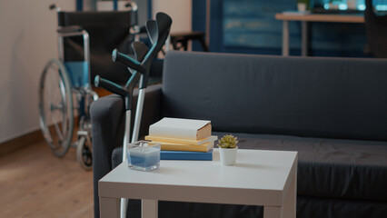 Nobody in living room with crutches and wheelchair for transportation. Empty space with walking support equipment used by people with chronic disability to have physical mobility.