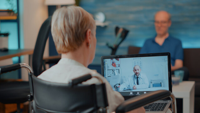 Aged woman attending online consultation with medic on teleconference call. Senior adult in wheelchair using remote videoconference to meet with specialist on laptop computer. Telemedicine