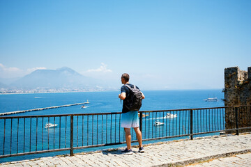 Back view of man traveler in top and shorts watching the sea from a view point in Turkey on a summer day