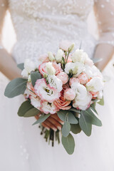 Wedding. A bride in a white dress holds a bouquet of white and pink flowers with eucalyptus greens in her hands