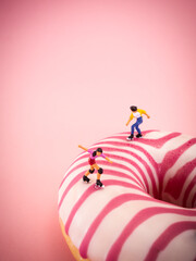 Donut in pastel pink colors, on a pink background. Roller skaters riding on a  sweet pink doughnut,...