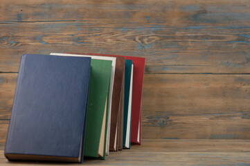 Stack of books on wooden table over rustic background with copy space