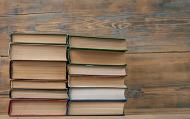 Stack of books on wooden table over rustic background with copy space