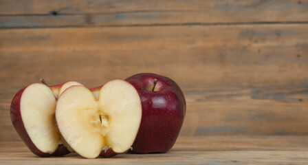 A composition of red apples, cut and whole, on a  wood background. Natural fruits. The half of apple. Space for your text.