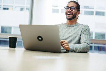 Cheerful businessman laughing happily in a co-working space