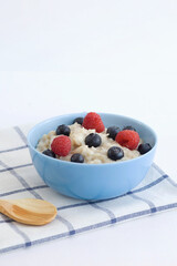 Milk porridge with berries. Blue plate with porridge