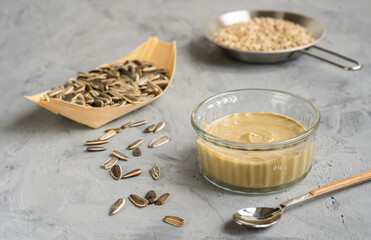 Homemade sunflower seeds' butter or spread with roasted seeds on grey background