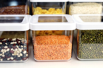Transparent containers filled with cereals on the shelf in kitchen. Organization of storage of bulk food