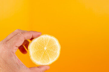 Limones sobre fondo naranja con mano desidratada