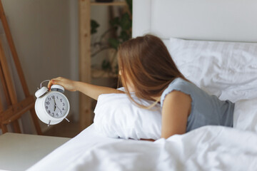 Woman sleep on the bed turns off the alarm clock wake up at the morning, Selective focus.Young woman reaching to turn off alarm clock ,early morning