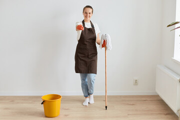 Hey you, choose our cleaning service. Full length portrait of smiling beautiful woman maid wearing...