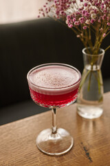 red alcoholic cocktail or lemonade with foam on the background of a beautiful restaurant, vertical image
