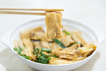 Pick up Tofu skin with chopstick. Bean product, also called yuba or soybean skin. Traditional...