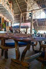 Wooden tables in cafe under a roof. Authentic interior of restaurant in Kendwa, Zanzibar, Tanzania.