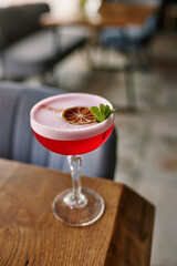red alcoholic cocktail or lemonade with foam on the background of a beautiful restaurant, vertical image
