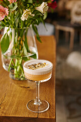 yellow alcoholic cocktail or lemonade with foam and a piece of dry lemon on the background of a beautiful restaurant, vertical image