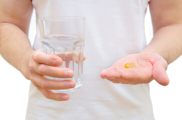 Man holding fish oil pill and glass of water