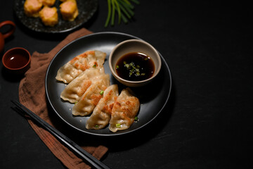 Flavorful Asian Chinese fried dumplings or gyoza on black table.