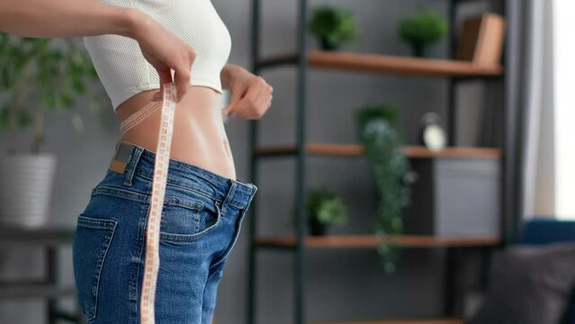 Closeup unrecognizable slim woman in oversize big jeans measurement waist weight loss liposuction