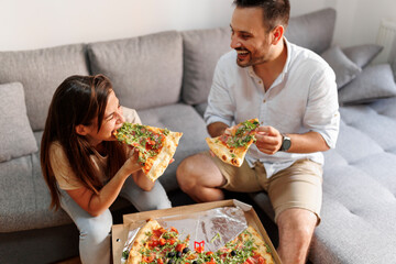 Couple having fun eating pizza at home