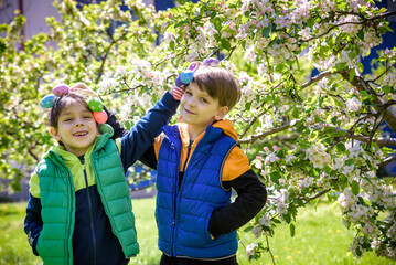 Two sibling brothers friends after successful egg hunt standing and smiling with Easter eggs in their hands. Traditional Easter hunt outdoors