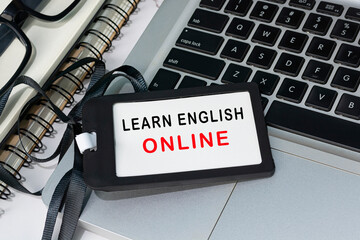 Learn english online text written on black name tag placed on a laptop.
