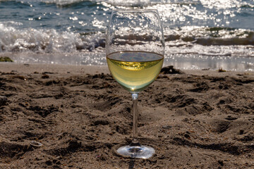 Romantic glass of white wine, on the sea beach. Wine tasting and relaxation at the resort