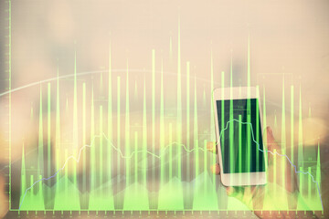 Double exposure of forex chart sketch hologram and woman holding and using a mobile device. Stock market concept.