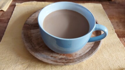 Große Kaffeetasse mit Milchgetränk. Nahaufnahme. Eine Holzplatte unter der Tasse. Gelbe...
