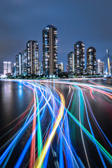 Vertical timelapse shot of colorful traffic lights with illuminated buildings in the background